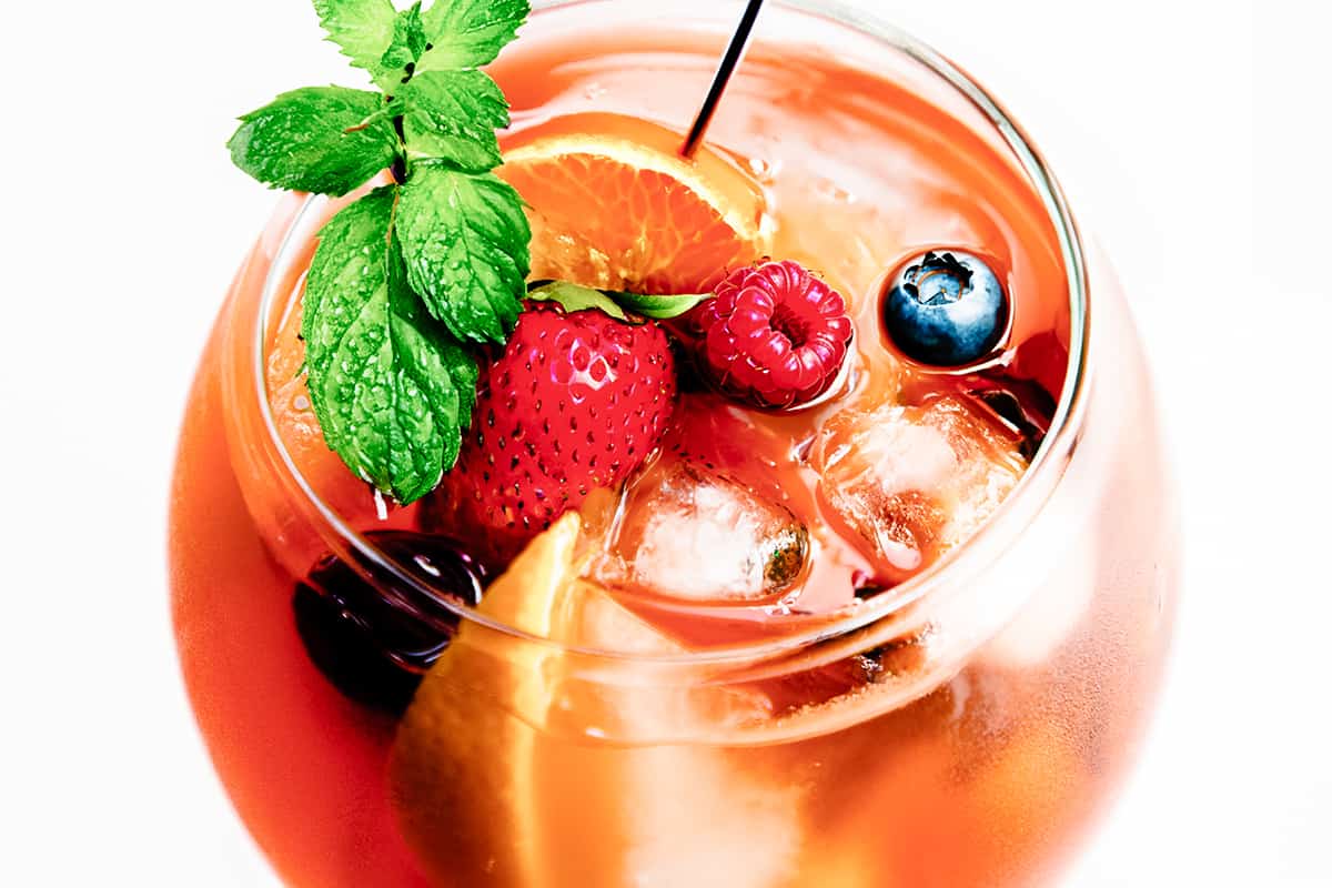 a close up image of a glass of Rosé Sangria with fresh fruit, mint and a cocktail stick in the glass.