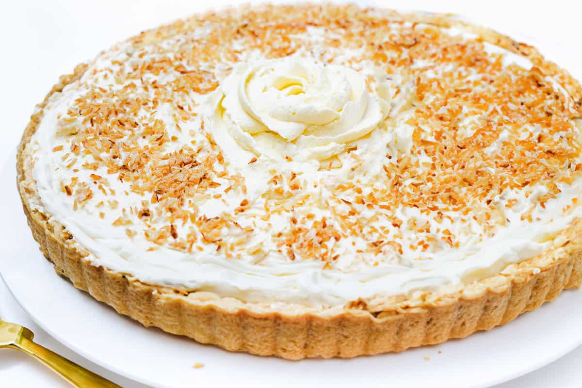 a full image of the coconut cream pie on a plate with a pie server next to it.