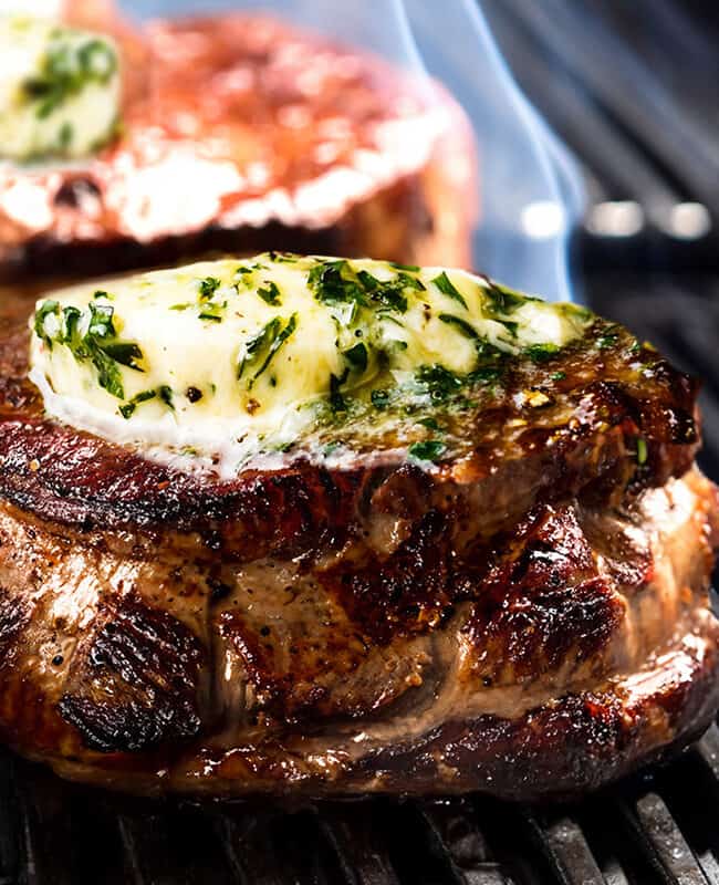 a close up image of herb and garlic butter added to the Grilled Filet Mignon on the grill.