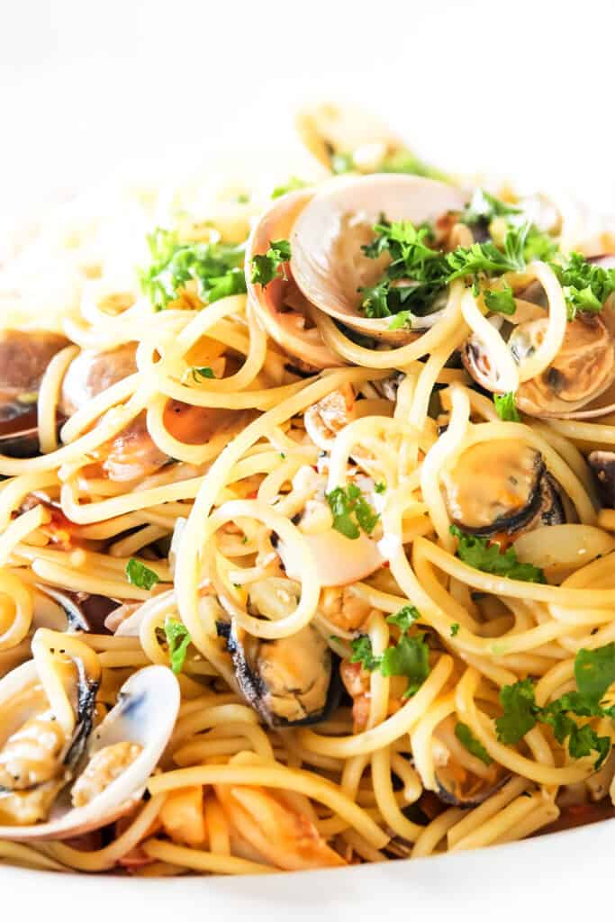 the spaghetti and white clam sauce served on a white plate.