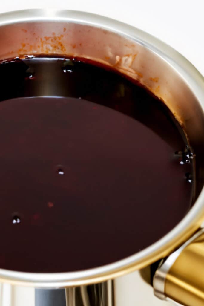 a pot of a glossy deep colored red wine sauce.