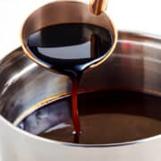 a ladle pouring red wine sauce into a saucepan