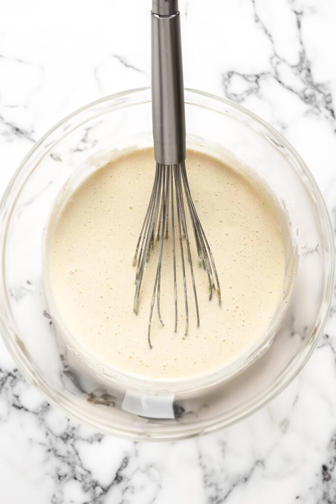 The ice cream base for cookies and cream ice cream in a bowl with a whisk.