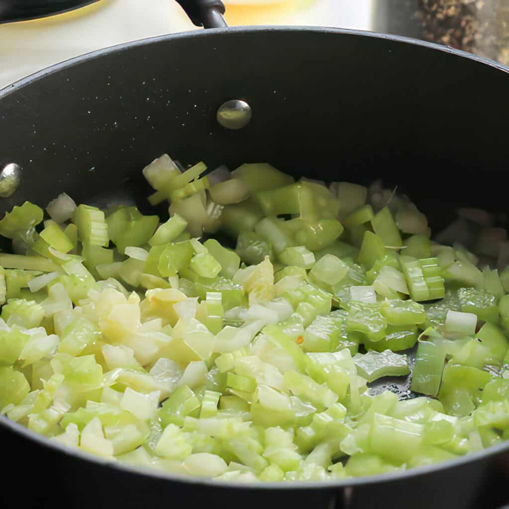 celery and onions cooking in a pan.