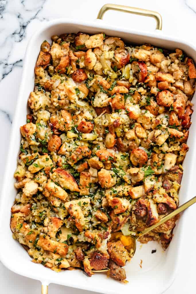 A pan of sausage stuffing with a serving spoon in the pan.