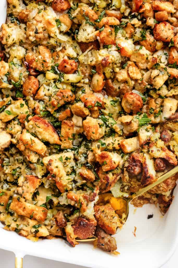 a close up image of a pan of sausage stuffing with a serving spoon in the pan.