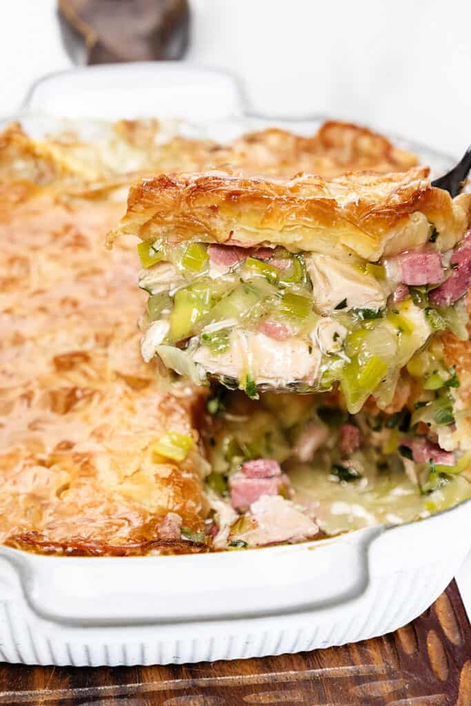 a serving spoon lifting a serving of the Turkey and Ham Pie from the baking dish.