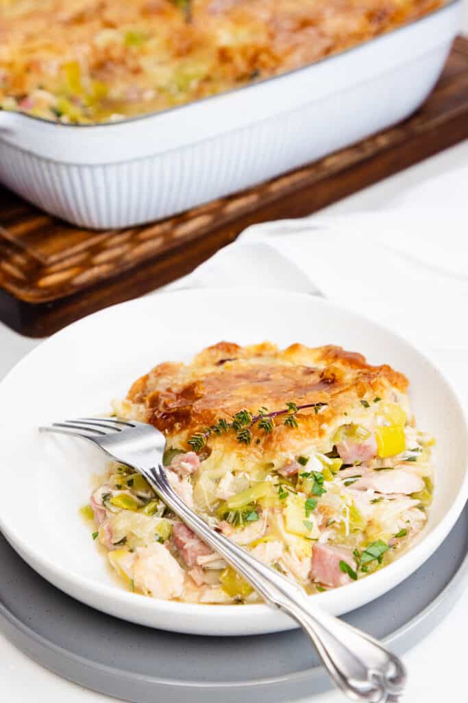 a serving of Turkey and Ham Pie on a dish with a fork.