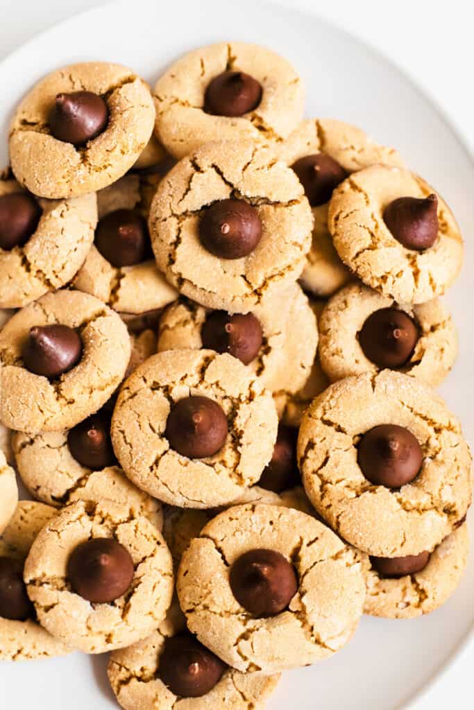 A plate of peanut butter blossom cookies with chocolate kisses in the center.