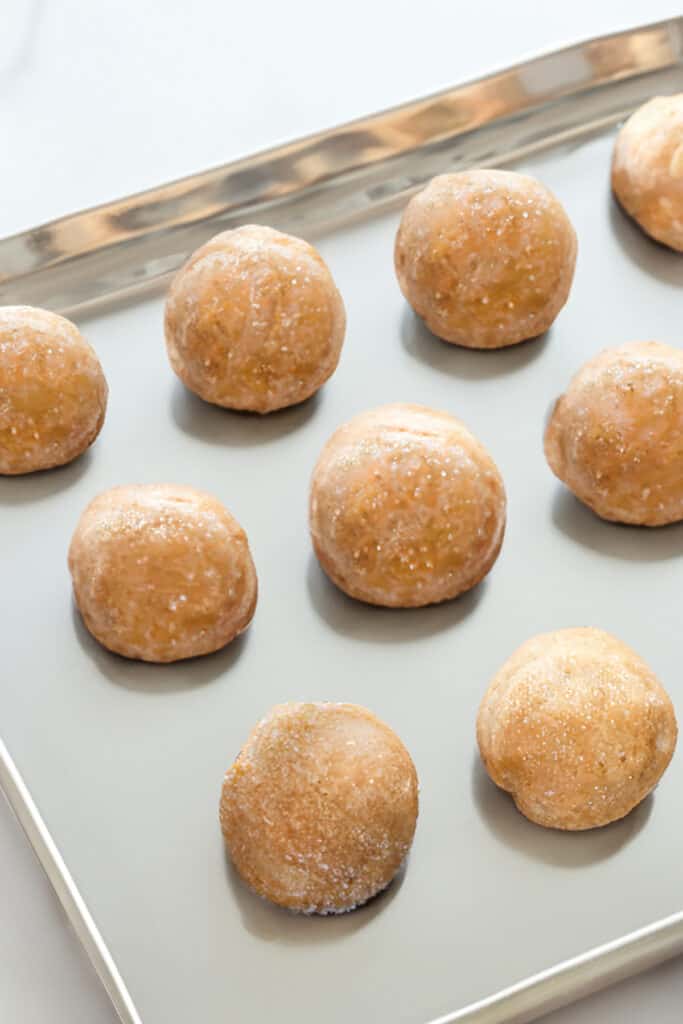 Sugared peanut butter cookie dough balls arranged on a baking sheet.