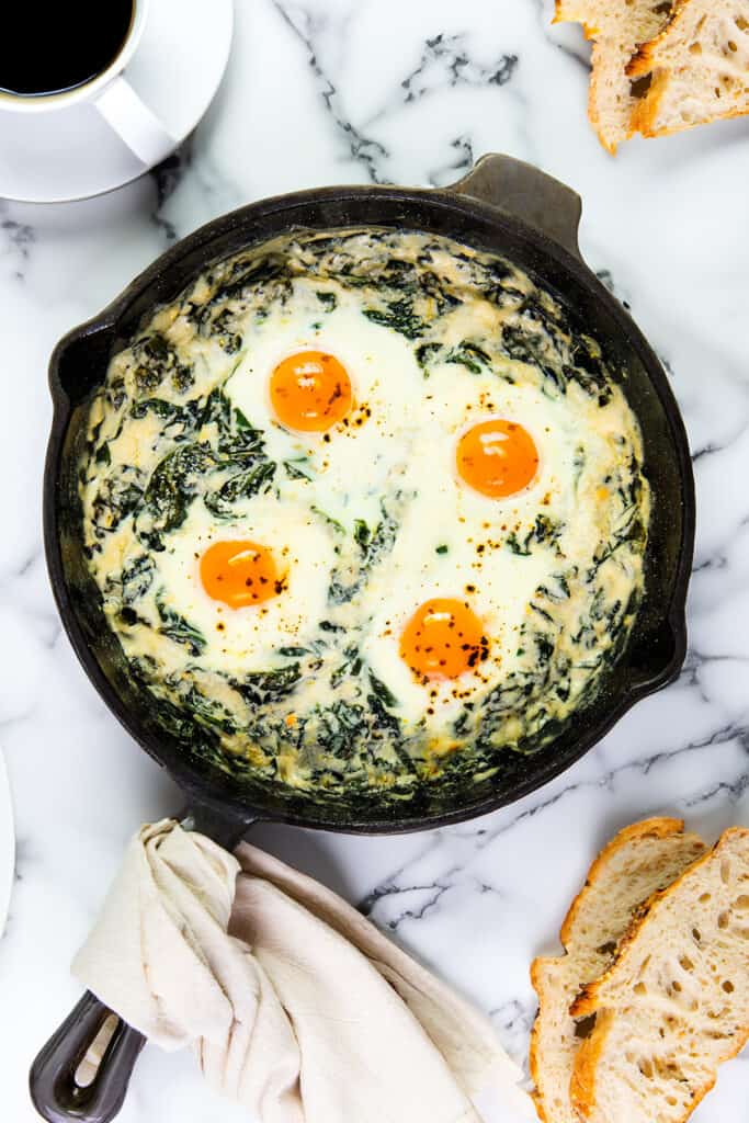 The Baked Eggs Florentine fresh from the oven on a table with coffee and toast.