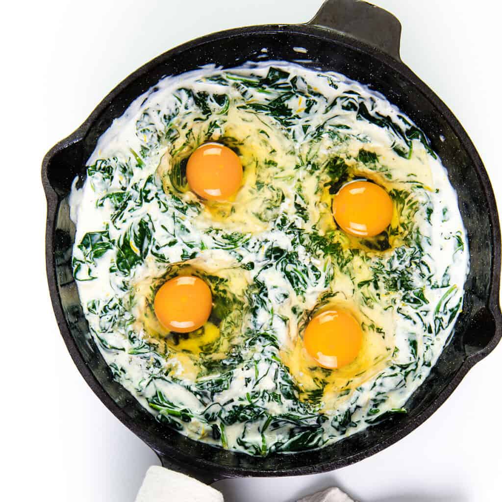 The eggs added to the spinach mixture in the pan.