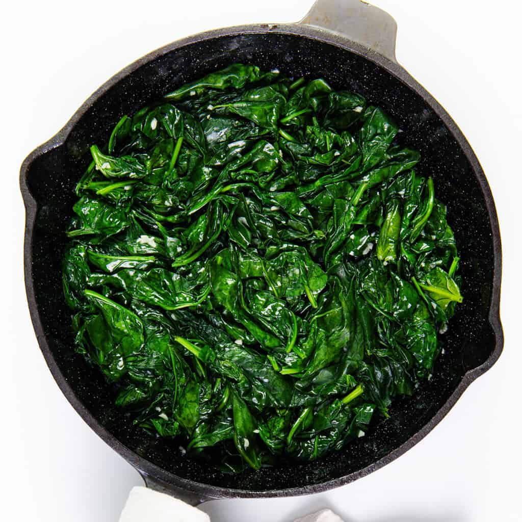 The cooked spinach and garlic in a pan.