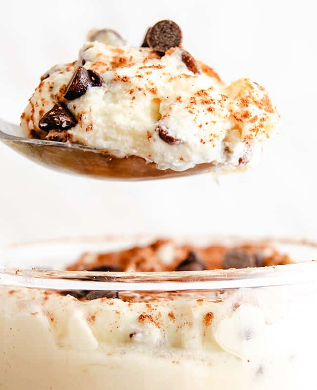 In the glass below, there's more of the creamy ricotta dessert, speckled with chocolate chips and a hint of cinnamon, being lifted by a spoon.