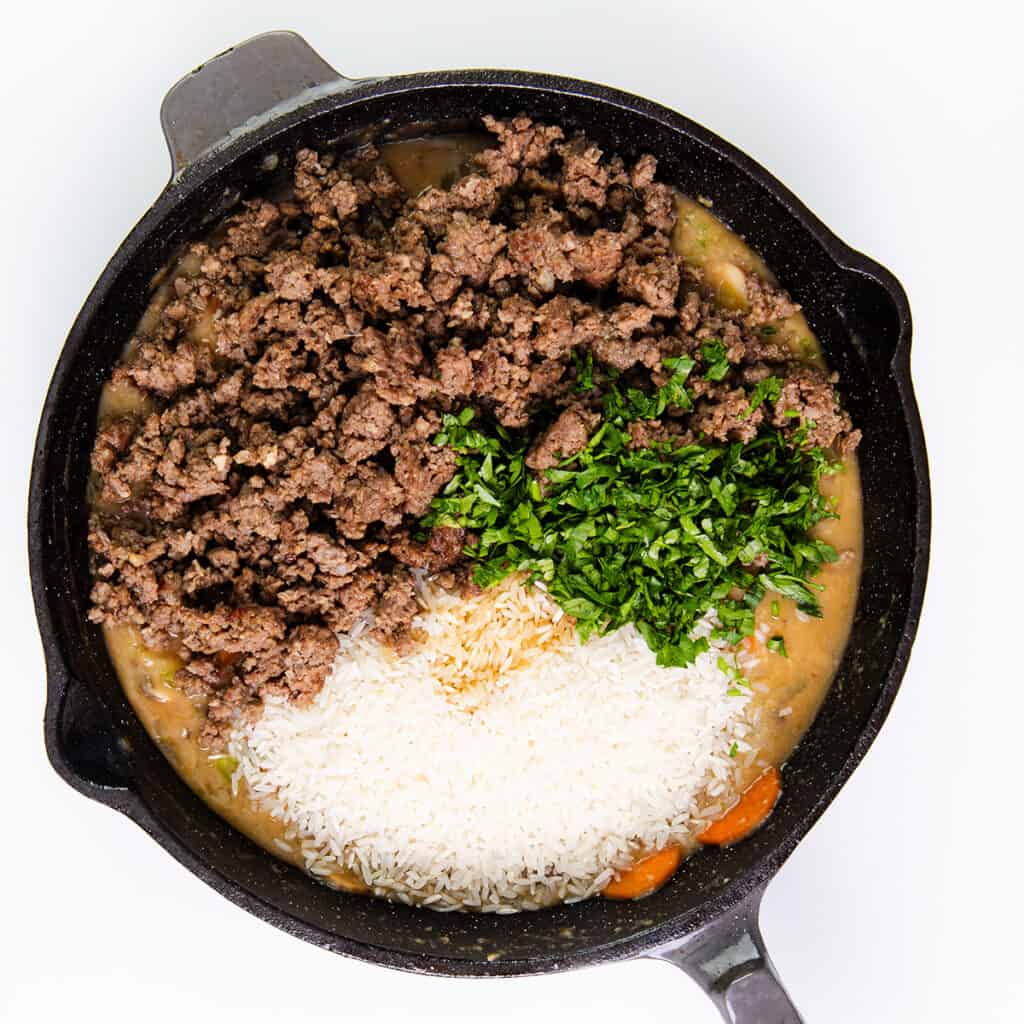 the ground beef, rice and herbs in the pan with the vegetables.