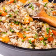 Skillet with hamburger and rice garnished with parsley, close-up.