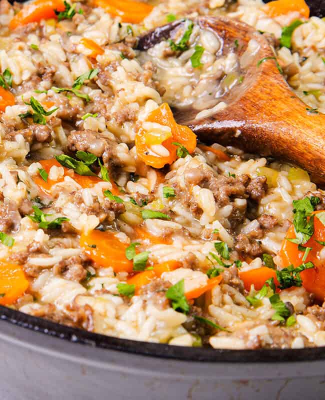 Skillet with hamburger and rice garnished with parsley, close-up.