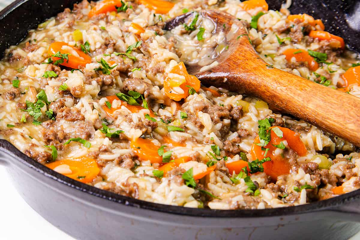 Skillet with hamburger and rice garnished with parsley, close-up.