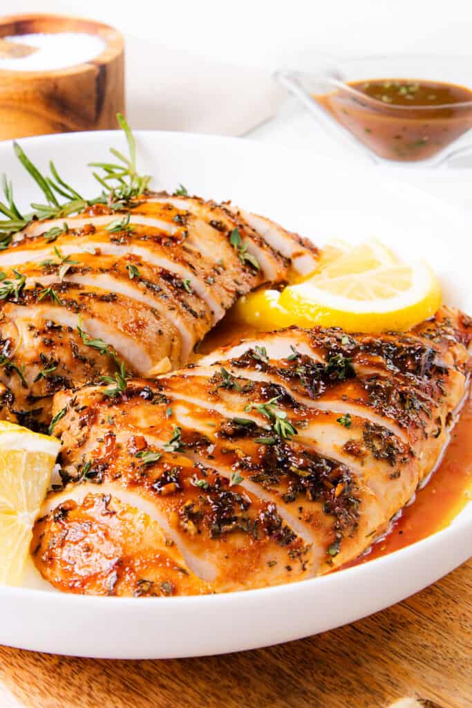 The image shows a juicy turkey tenderloin, sliced and served with rosemary and lemon, covered in a herby sauce. It looks well-cooked and tasty.