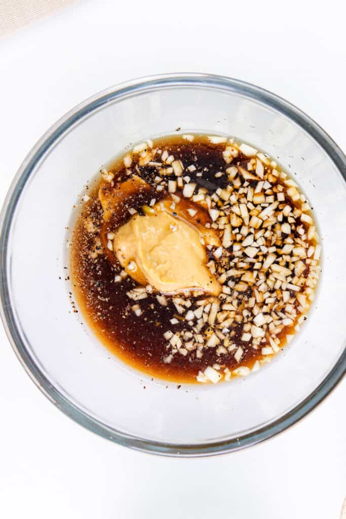 A glass bowl with the ingredients for the marinade in it.