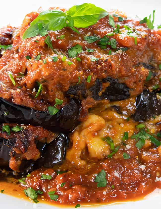 Baked Eggplant Parmesan on a white plate topped with fresh basil