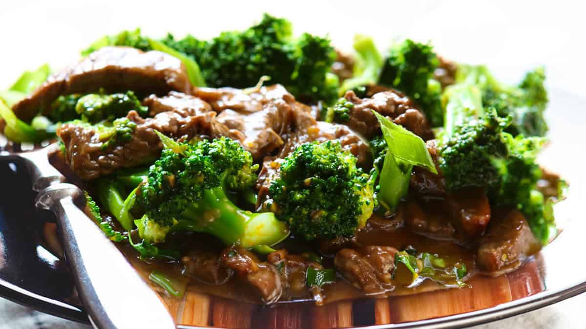 a close up image of a dark colored plate piled high with a Beef and Broccoli Stir Fry.