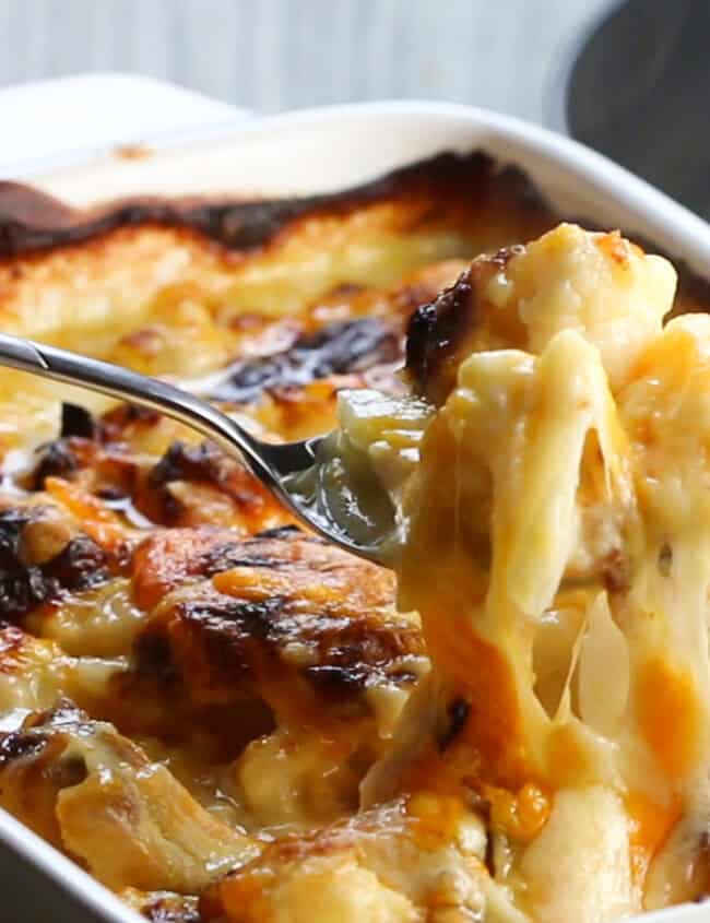 A spoon serving Cheesy Cauliflower from a pan.