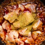 Chicken pieces with spices in a pot, ready to be cooked.