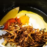 Spices, fried onions, and yogurt in a pot, ready for cooking.