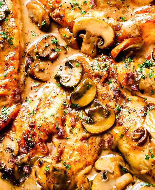 A close up image of A cast iron pan filled with chicken marsala and mushrooms.