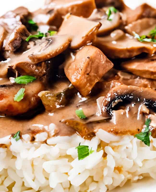 A close up image of Chicken Stroganoff on a white plate with a white background.