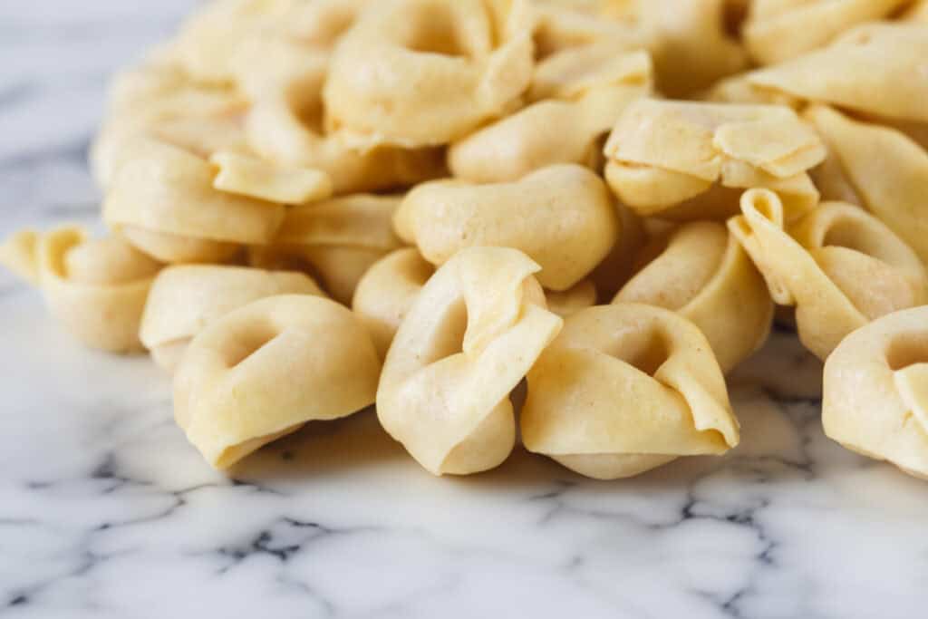 Fresh Tortellini piled on a marble surface,