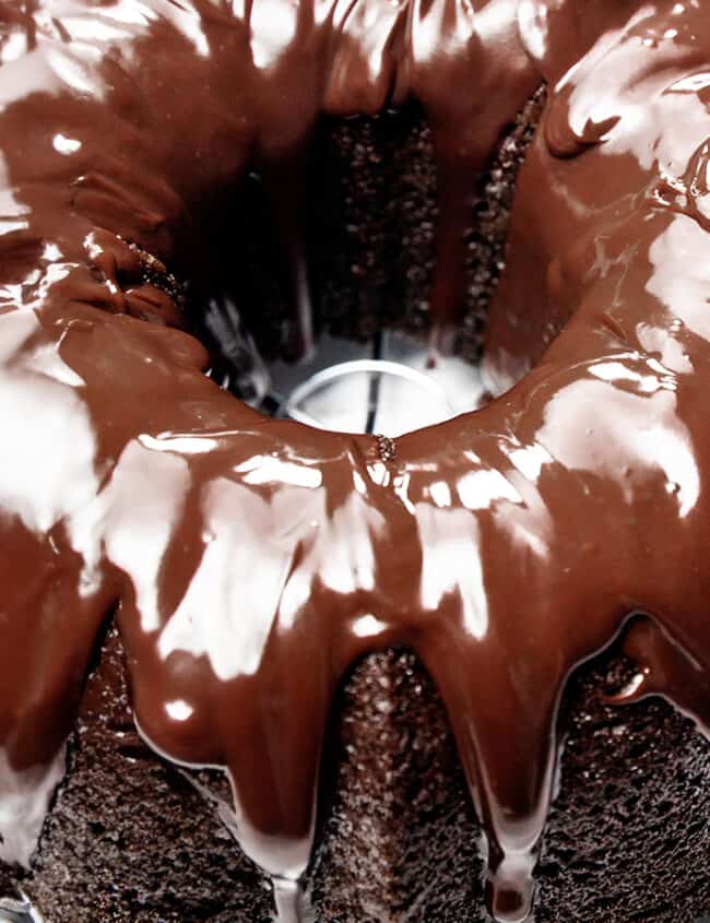 A moist chocolate bundt cake with chocolate frosting on a plate.