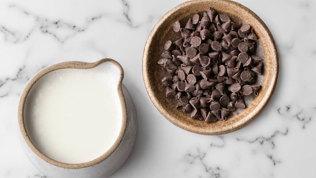 a marble table with a bowl of chocolate chips and a jug of buttermilk.