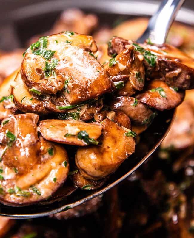 a spoonful of sautéed mushrooms being served.