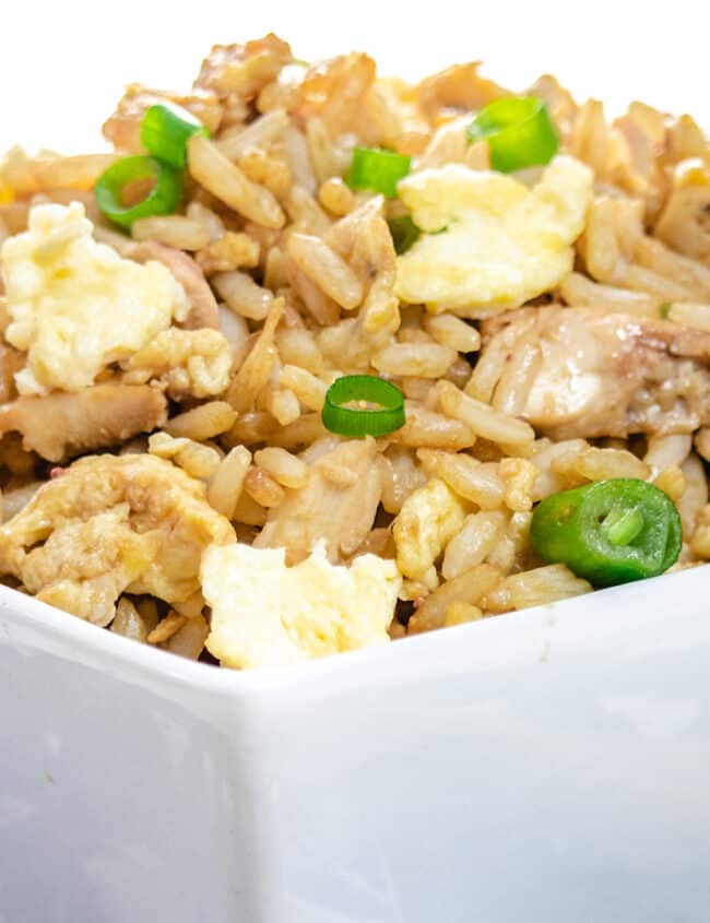 A close up of a bowl of fried rice with chop sticks next to it.