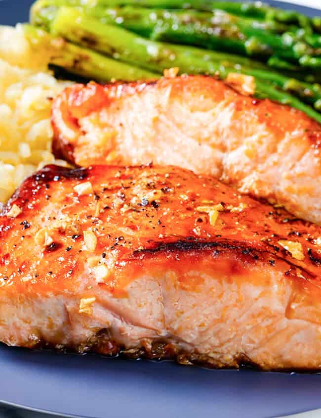 Two pieces of garlic butter salmon with roasted asparagus and rice pilaf.