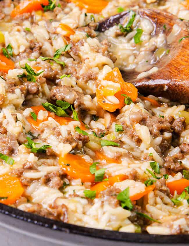 A skillet with hamburger and rice garnished with parsley, close-up.