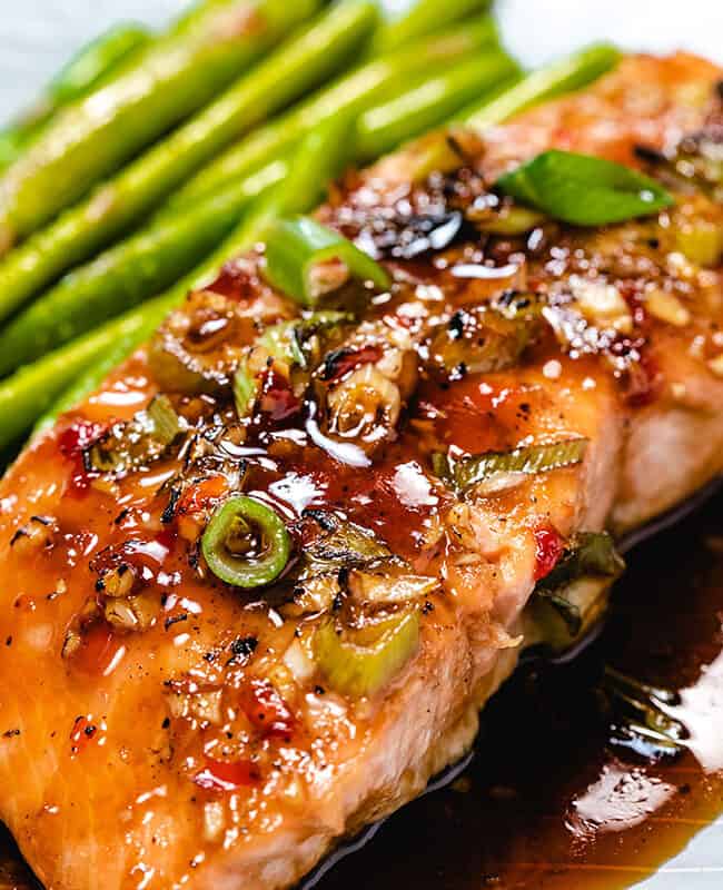 glazed salmon on a plate with asparagus next to it.