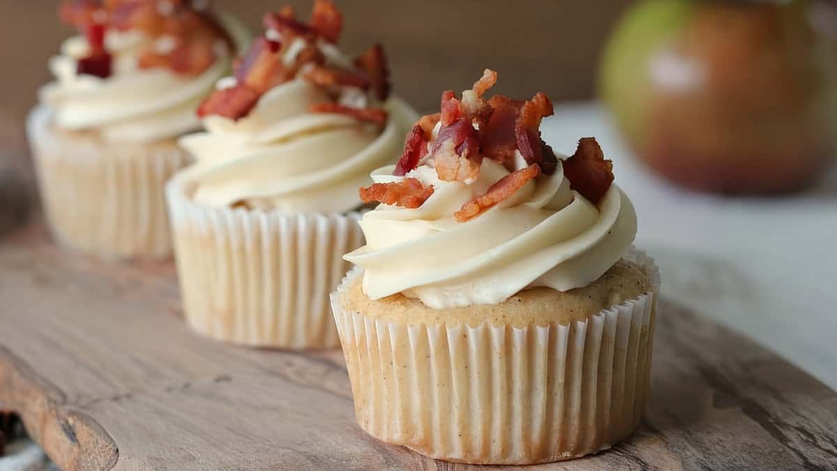 Cupcakes topped with a swirl of frosting and chopped bacon.