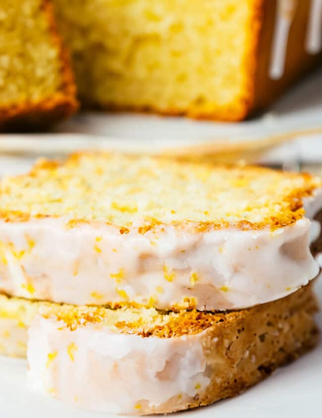 A sliced lemon pound cake with icing and lemon zest.