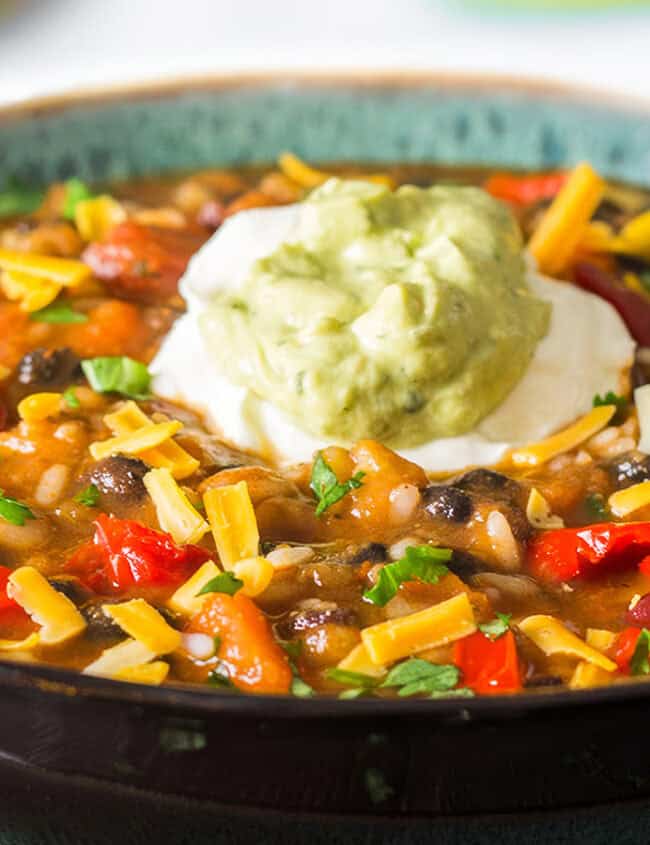 a bowl of Mexican soup topped with Guacamole and sour cream.