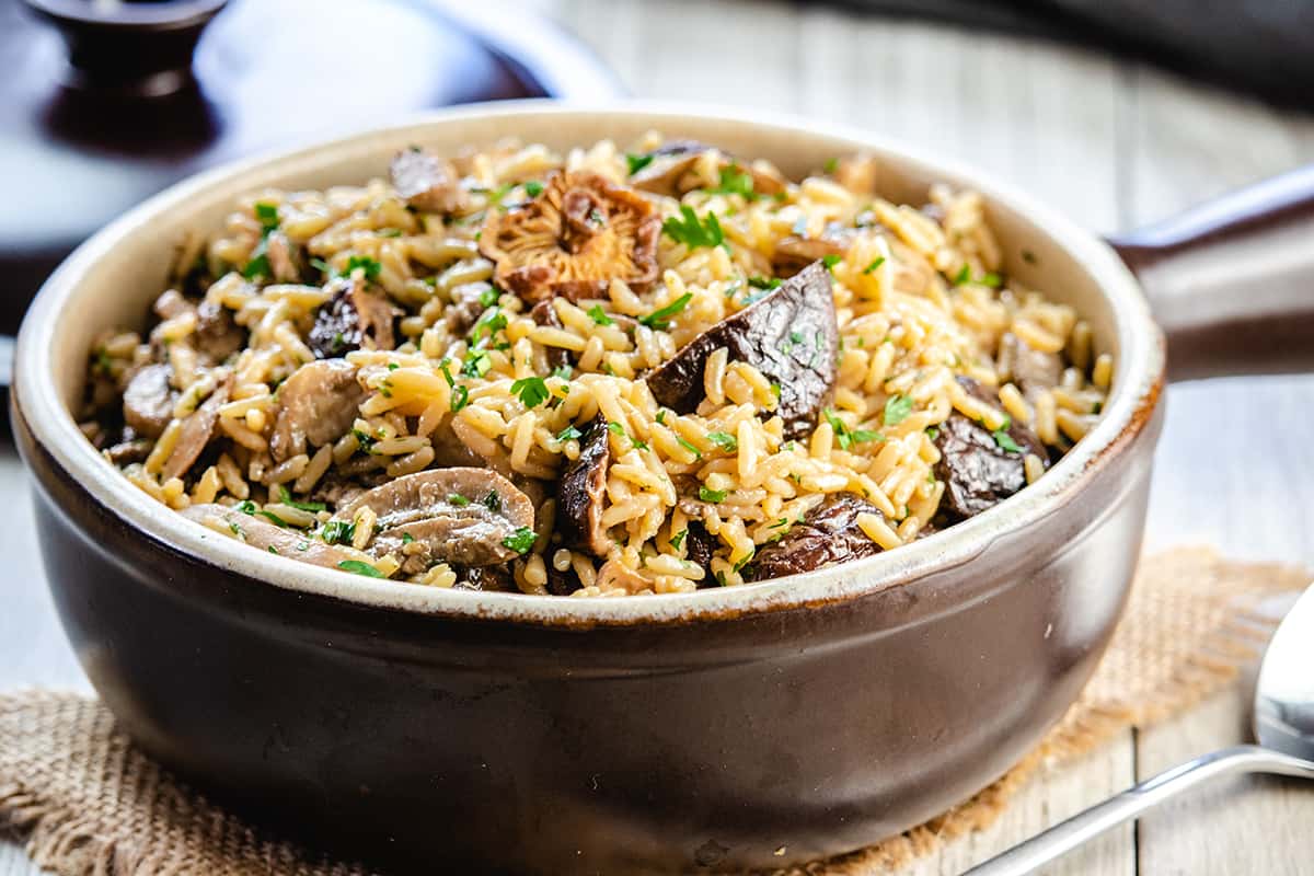 mushroom rice pilaf in a serving dish with the lid behind it