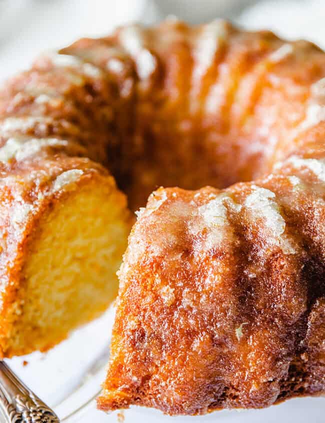 An orange Bundt cake on a glass cake stand.