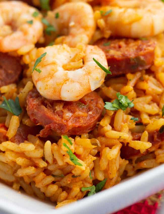 A plate of bright yellow saffron rice topped with chorizo and shrimp.