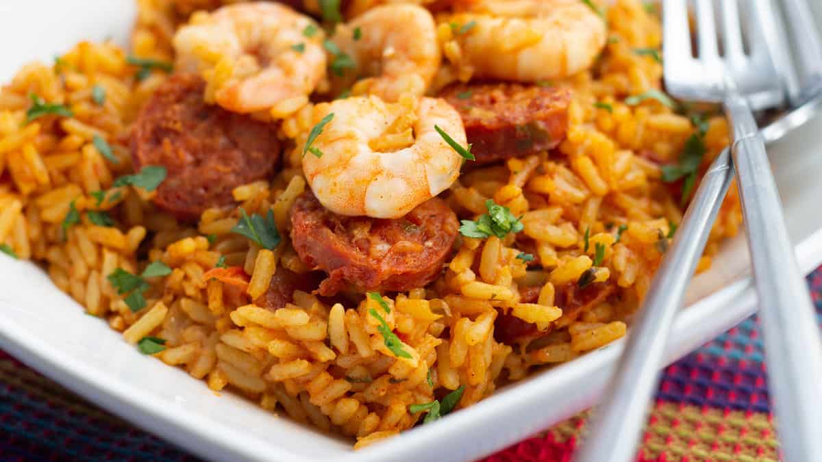 A plate of bright yellow saffron rice topped with chorizo and shrimp.