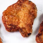 Golden and crispy panko-breaded pork chops resting on paper towels to drain excess oil.