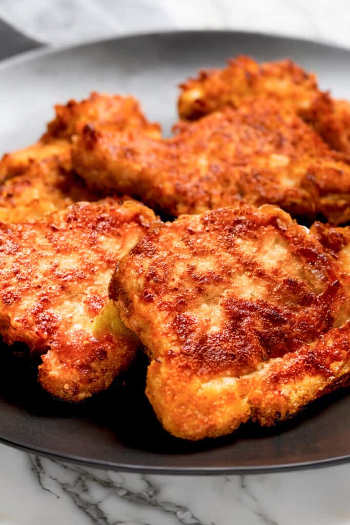 Golden brown panko-breaded pork chops arranged on a dark plate, ready to be served.