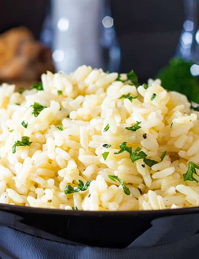 A bowl of rice Pilaf in a dish with salt and pepper mills in the background.