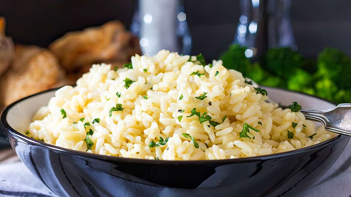 A bowl of rice Pilaf in a dish with salt and pepper mills in the background.